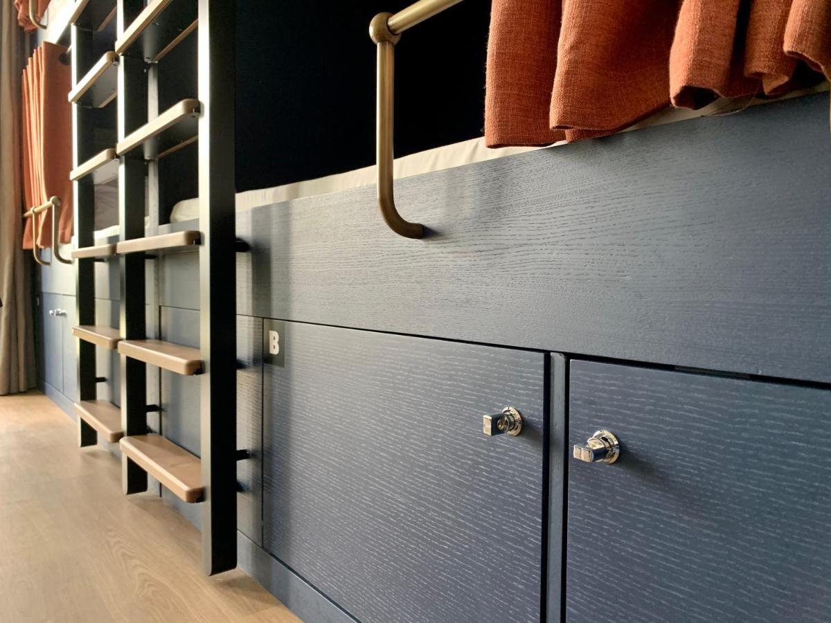 The People - Paris Nation Hostel Exterior photo The photo shows a corner of a room featuring modern furniture. The focus is on a dark blue wooden surface with two small cabinet doors that have metallic knobs. Above the cabinets, there is a decorative railing made of metal. To the left, you can see